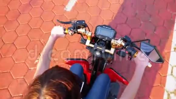 在度假小镇上一个骑着棕榈树的红色自行车道上骑着电动滑板车的女人视频的预览图