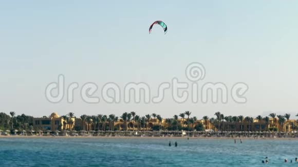 风筝上的降落伞在水面上盘旋靠在晴朗的蓝天上夏天在海滩上视频的预览图
