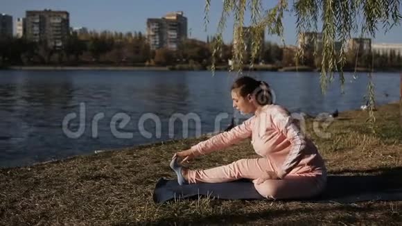 美丽的女孩穿着运动服在城市海滨做瑜伽视频的预览图