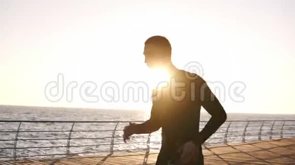 年轻的慢跑者在长跑前停下来休息一下他穿着一件白色的黑色运动衫视频的预览图