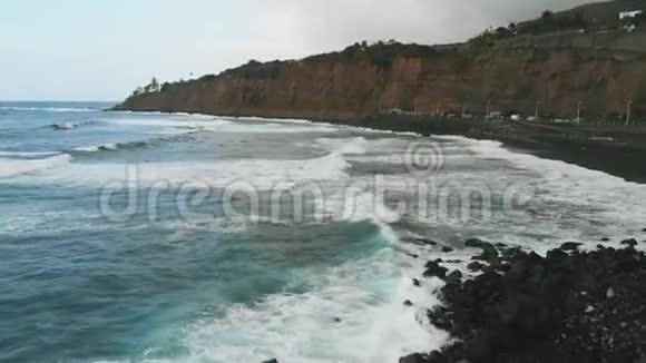 空中观景美丽的绿松石色彩的波浪随着黑色的沙子落在海岸上TenerifePlayadelSocorro视频的预览图