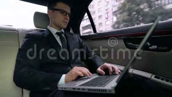 微笑的商人在笔记本电脑上读好消息是的在车后座上做手势视频的预览图