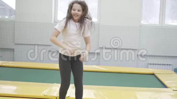 快乐的少年女孩跳在蹦床上视频的预览图