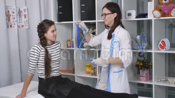 友好的女医生在医院的房间里检查一个十几岁的女孩医生倾听呼吸视频的预览图