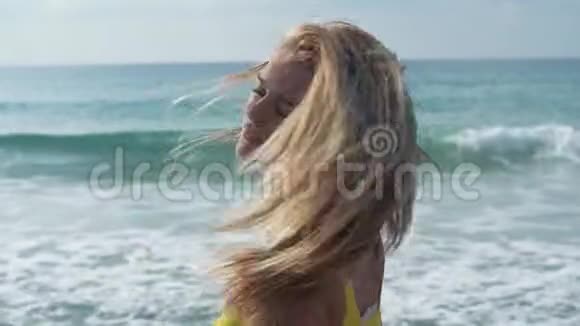年轻的金发女人摇了摇头使头发在海洋背景上飘扬孤独的女孩在海上度过时光视频的预览图