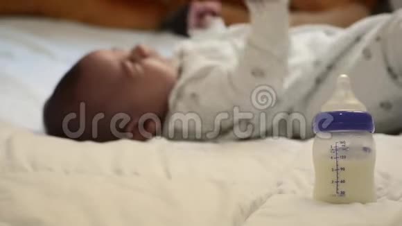 婴儿奶瓶床上放着母乳而几个月大的树宝宝正在哭视频的预览图