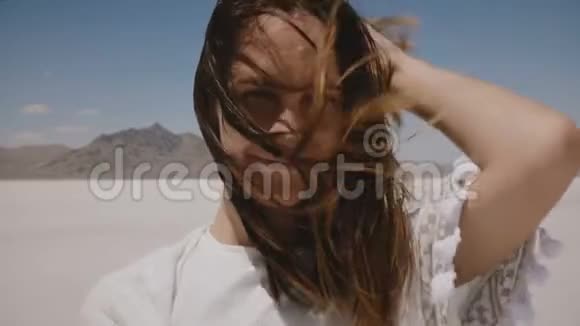令人惊叹的特写生活方式肖像迷人的年轻女子微笑着飞翔的头发和雀斑在盐漠湖视频的预览图