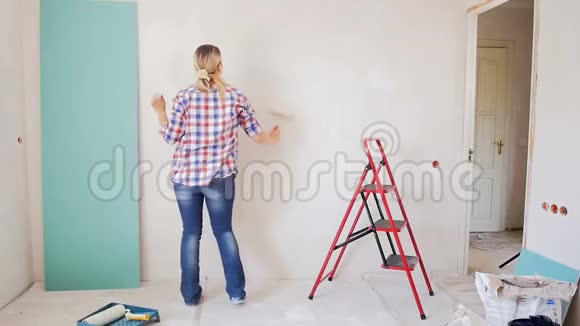 慢镜头的快乐年轻女子跳舞时在她的公寓墙画年轻女孩正在装修视频的预览图