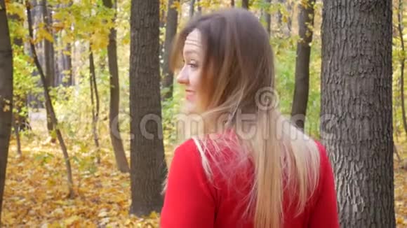 可爱的女人在秋天的公园里旋转和微笑视频的预览图