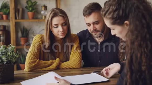 女房地产经纪人正在向年轻夫妇宣读买卖协议男子正在签署文件并拿钥匙摇晃着视频的预览图