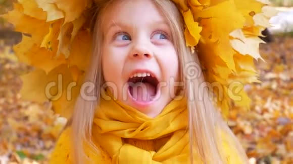 秋天戴着黄色围巾和花环的小可爱女孩正在公园里微笑视频的预览图