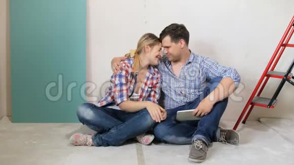 一对幸福的年轻夫妇坐在正在装修的新房子的地板上放松视频的预览图