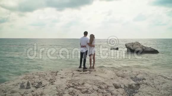 站在海边的年轻夫妇要欣赏美丽的海景男人和女人互相拥抱年轻人的休闲视频的预览图