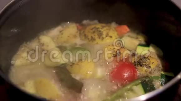 蔬菜煮汤在炉子上的锅中煮上面有草药的自制汤视频的预览图