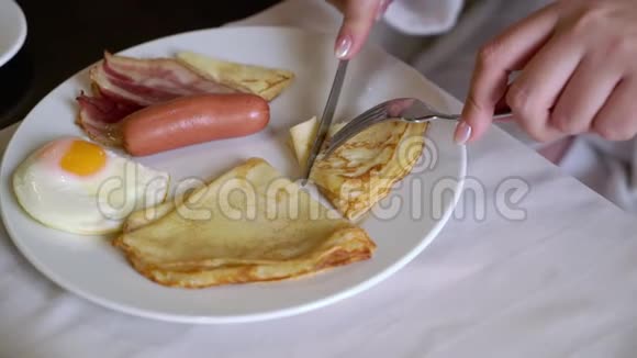 早上吃早餐的女人盘子里有煎鸡蛋煎饼和香肠视频的预览图