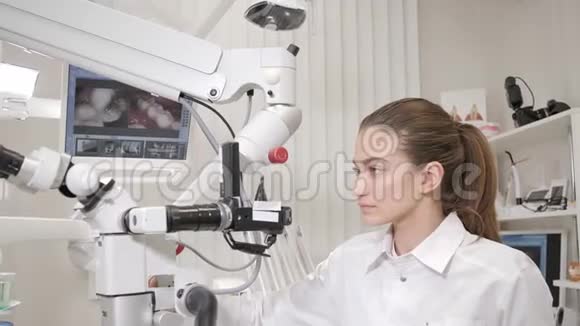迷人的漂亮女孩医生牙医使用显微镜年轻的非裔美国男子牙科诊所的椅子视频的预览图