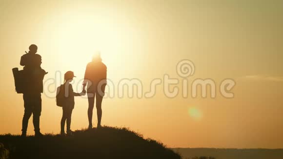 日落时父母和两个孩子在山上散步剪影幸福美丽的家庭视频的预览图