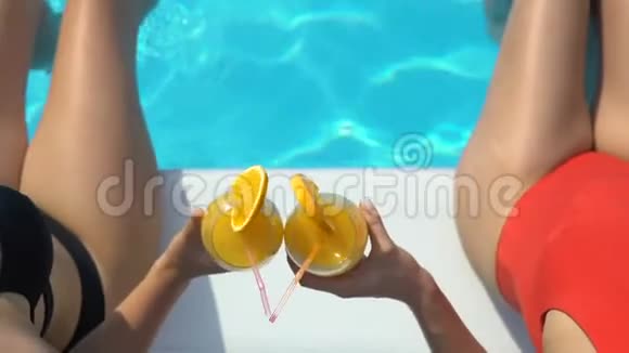 美丽的女士们在喝着鸡尾酒一边玩水一边看着镜头视频的预览图