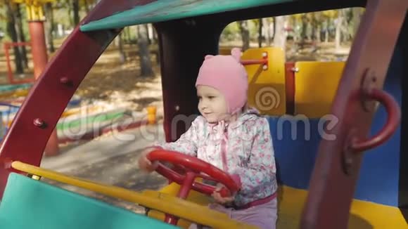 秋天的一天小女孩在操场上玩耍孩子坐在玩具车里视频的预览图