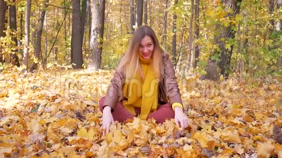 秋天可爱的女人在公园里扔或扔树叶树的背景视频的预览图
