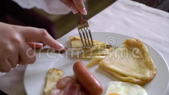 早上吃早餐的女人盘子里有煎鸡蛋煎饼和香肠视频的预览图