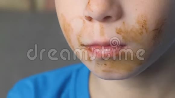 格里米快乐的少年正坐在沙发上吃巧克力糖不健康饮食观念嘴巴特写视频的预览图