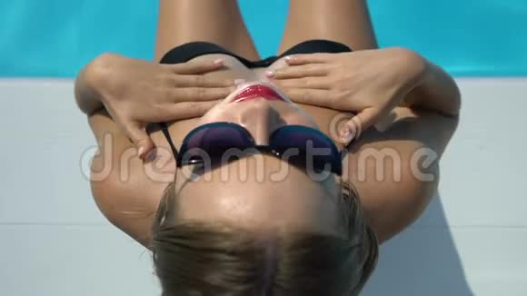 快乐的女性在游泳池附近微笑皮肤上涂防晒霜晒黑视频的预览图