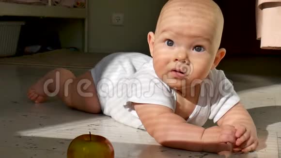 微笑的婴儿试图抓住地板上的苹果视频的预览图