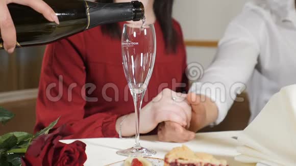 年轻夫妇双手放在桌子上的中弹服务员慢吞吞地给情侣倒香槟酒让他们浪漫视频的预览图
