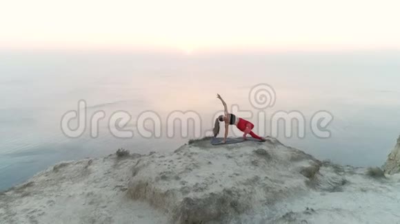美丽的女人正在做瑜伽Vasisthasana山顶的侧帆船日落时的海景视频的预览图