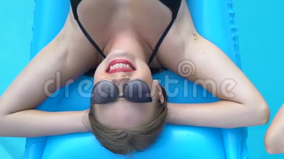 两位戴墨镜的美女躺在游泳池的床垫上度假视频的预览图
