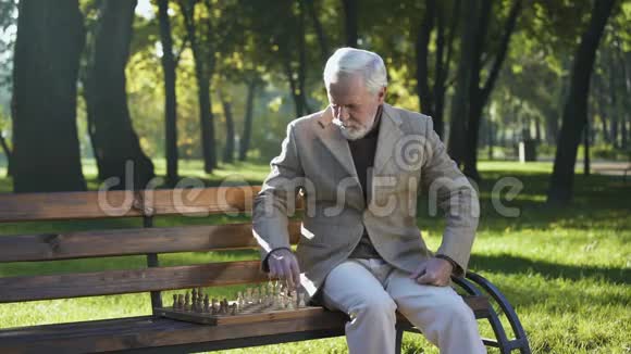 一个人坐在公园的长凳上下棋退休福利视频的预览图