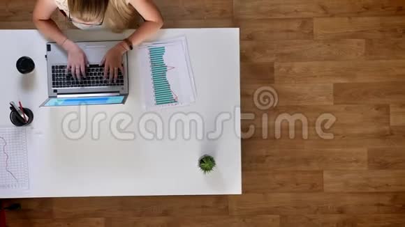 两个女人坐在办公桌前用木制背景和打字上面的镜头移动镜头有动力蓝色屏幕视频的预览图