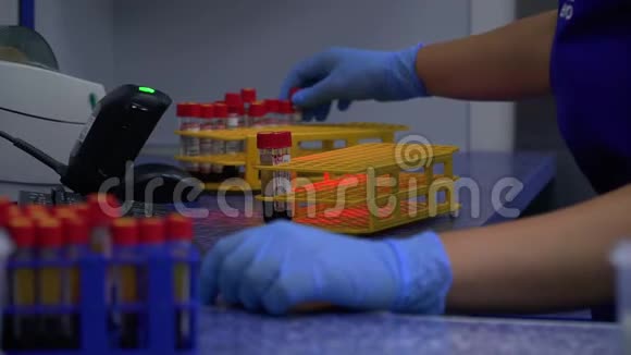 一名实验室技术人员手中拿着血管测试背景是一架彩色试管和其他病人的血样视频的预览图