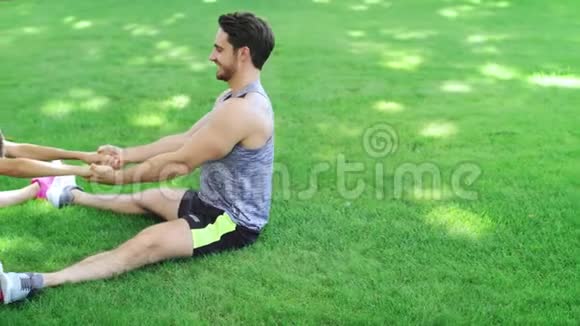 快乐的一对男女在夏天公园的草地上做伸展运动视频的预览图