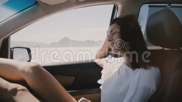 特写POV拍摄的快乐放松的女人头发随风飘动在盐湖沙漠的汽车乘客座位上视频的预览图