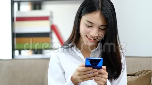 亚洲年轻女子在家玩手机看短信视频的预览图