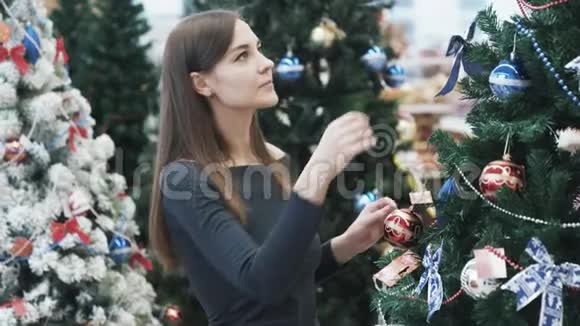 年轻的美女在超市为圣诞树挑选装饰品视频的预览图