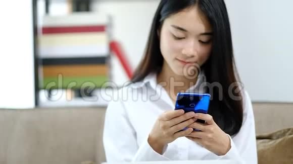 亚洲年轻女子在家玩手机看短信视频的预览图
