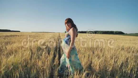 日落时一位怀孕的年轻女子正走在麦田上录像正在播放视频的预览图