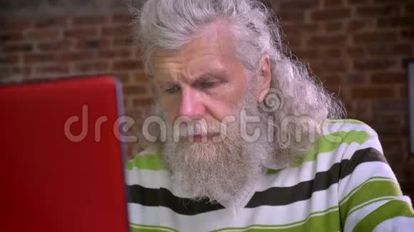 老可爱的白种人男性在砖房工作孤立地坐着不再用笔记本电脑揉眼睛视频的预览图