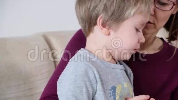 可爱的小男孩在咳嗽和他的母亲坐在客厅里视频的预览图