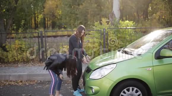 两个女孩试图打开汽车引擎盖给一个死电池充电视频的预览图