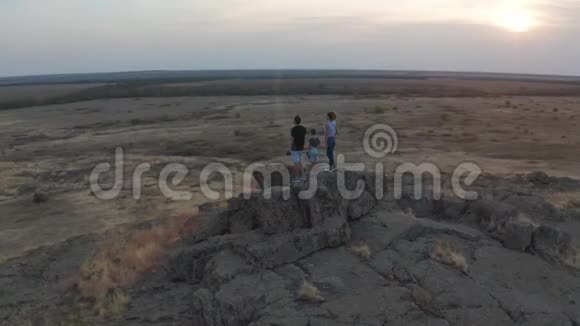 空中观景一家人站在山上母亲父亲和儿子去山里远足日落视频的预览图