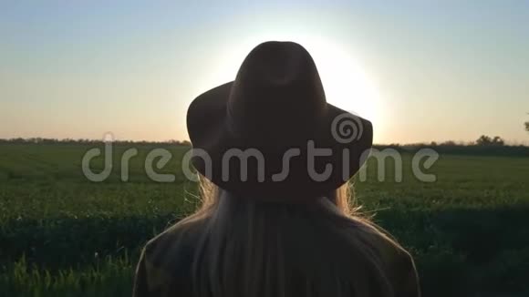 一个可爱的年轻女子旅行者或农民看日落或日出穿着格子衬衫和帽子美丽的无忧无虑视频的预览图