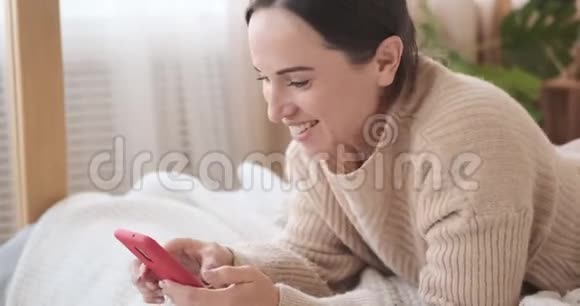 女人在床上玩手机视频的预览图