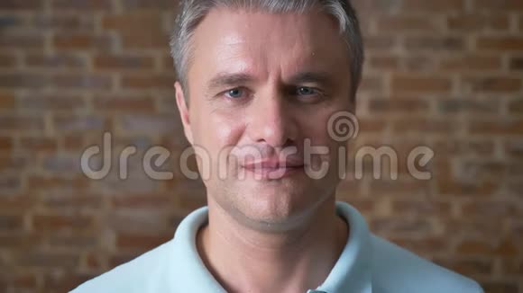 一张超帅的白种人男性特写脸直看镜头不眨在红砖办公室里随意的样子视频的预览图