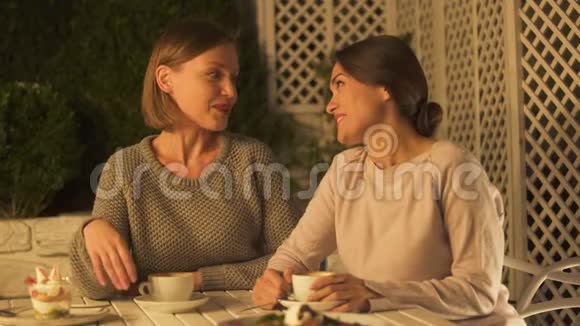 快乐的姐妹坐在露台上喝咖啡聊天拥抱信任视频的预览图