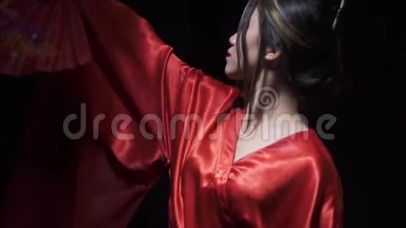漂亮的亚洲女人抬起头上的红色扇子然后遮住她的脸视频的预览图