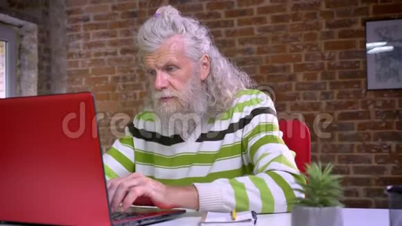 可爱的古代男性坐在他的工作场所精确地看着相机白色的长胡子和头发滑稽的样子视频的预览图